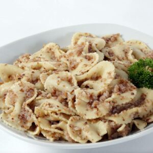 A plate of 5 LBS - Kasha Varnishkas bow tie pasta and buckwheat, garnished with a sprig of parsley on the side.