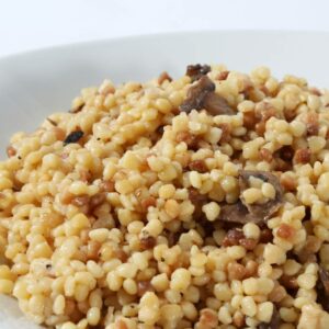 A close-up of a plate of 5 LBS - Egg Barley & Mushroom, showing the cooked egg barley mixed with mushrooms and small pieces of meat.